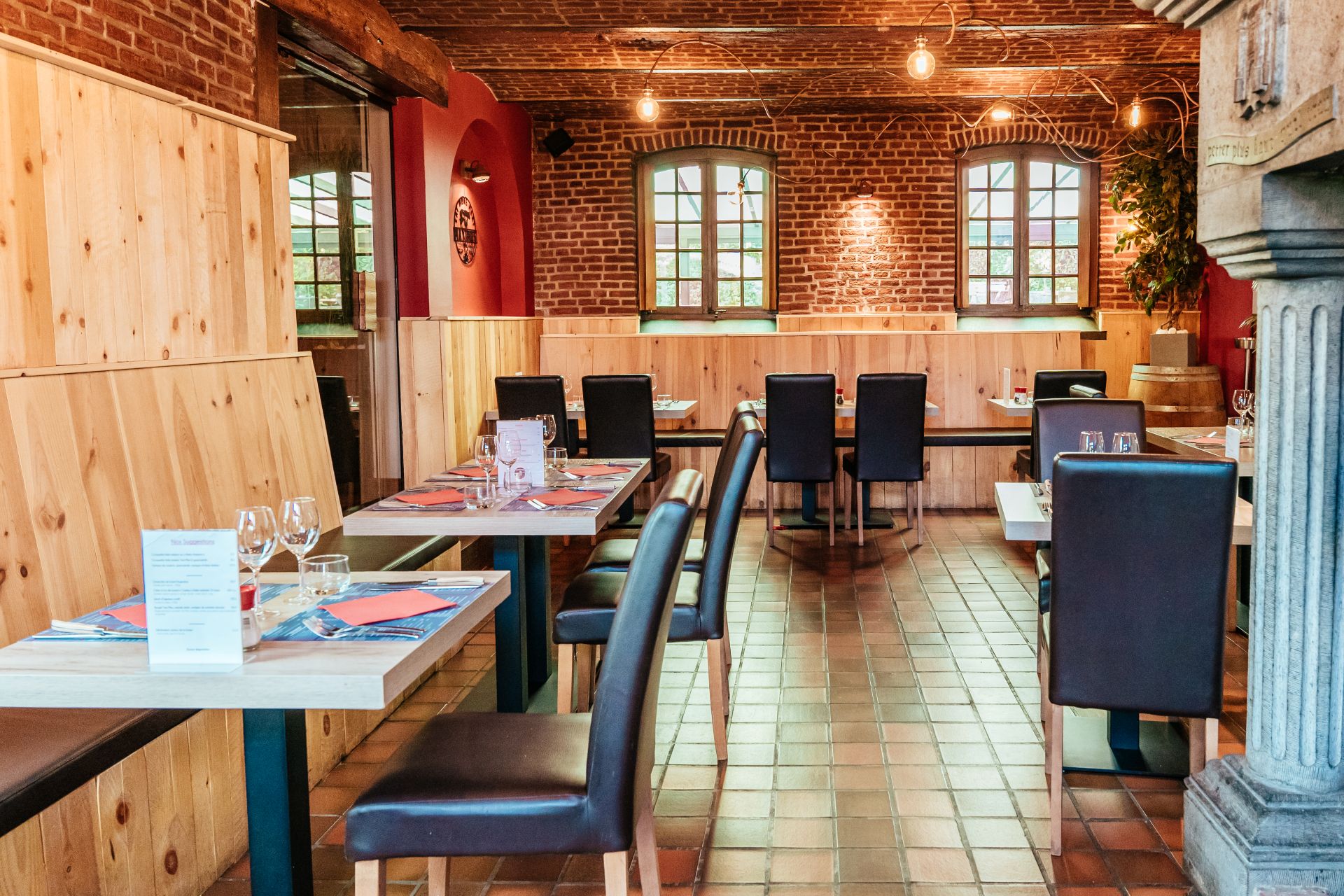 Vue de l'intérieur du restaurant Maximus Steakhouse Mons. Tables et chaises bien alignées.